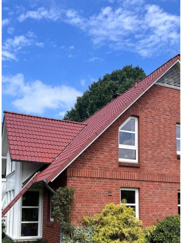 Dasselbe Haus mit frisch beschichtetem, kräftig rotem Dach
